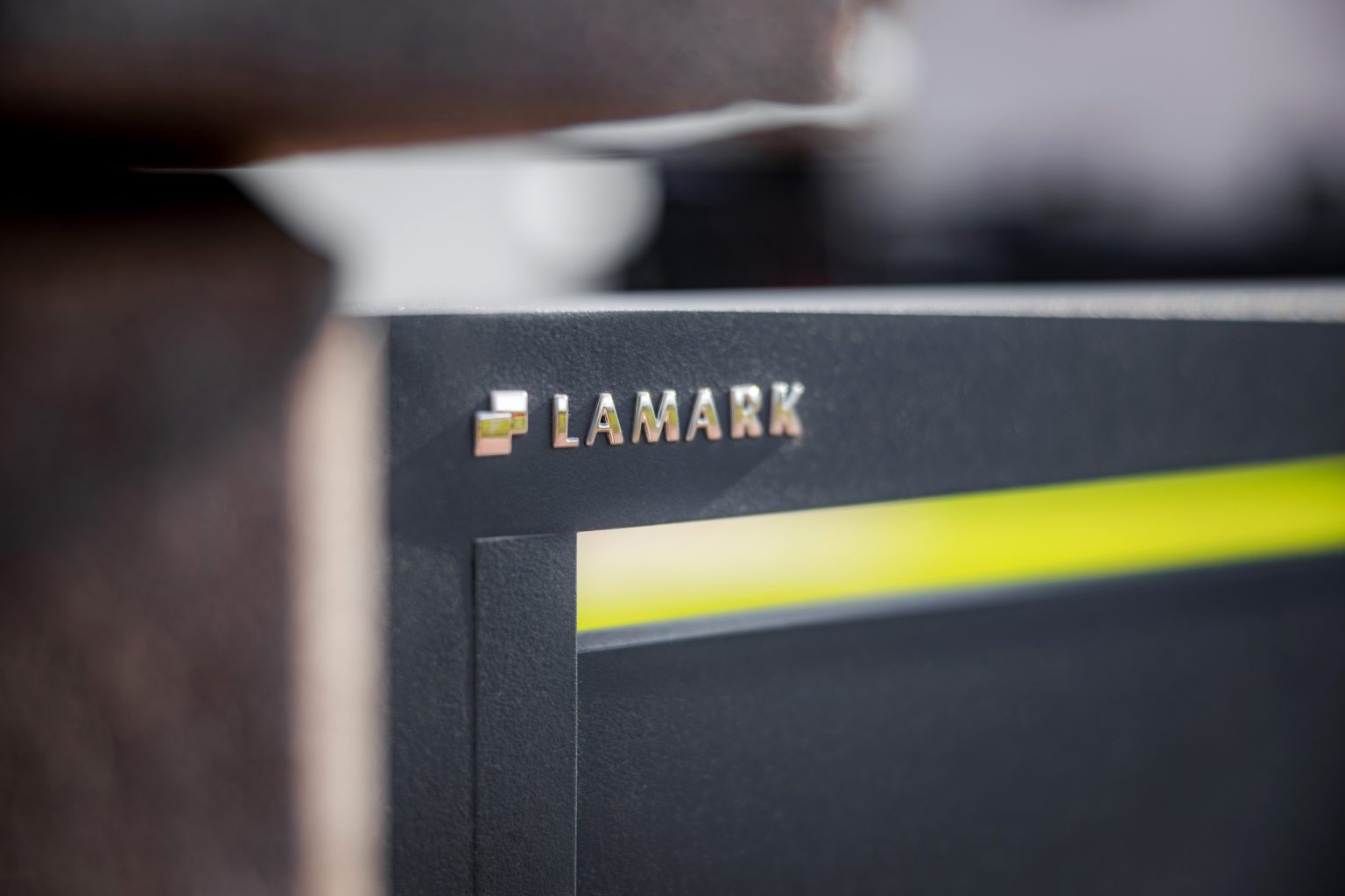 Detail loga LAMARK na deskové brance | Motiv Lobon | Šedá antracitová barva | Betonové sloupky